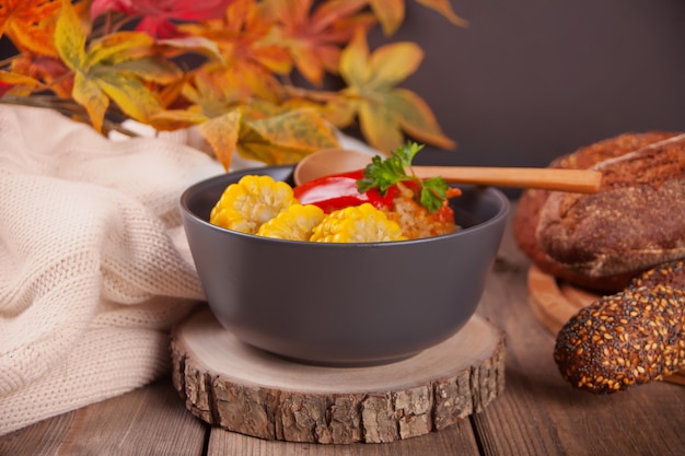 Foto pimentos recheados com carne picada, arroz e milho na tigela em cima da mesa de madeira