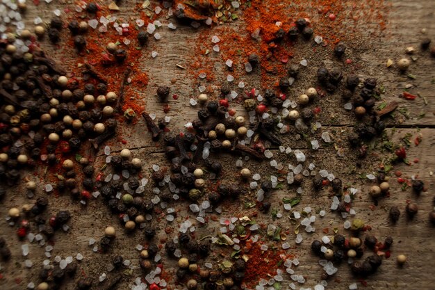 Pimienta blanca y negra guisantes sal marina pimiento rojo polvo clavo especias sobre un fondo de madera