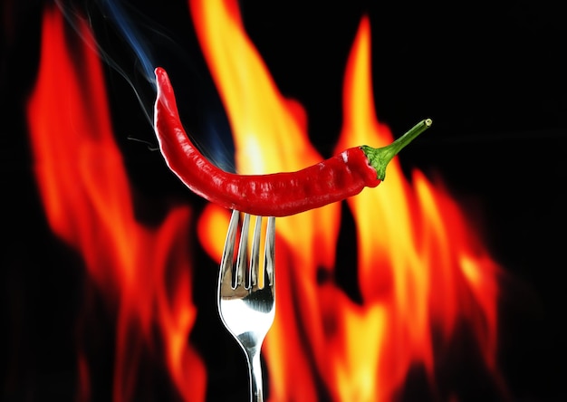 Pimienta picante roja en horquilla sobre fondo de fuego