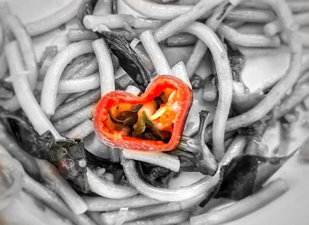 Pimienta roja del corazón en el fondo abstracto de la comida de la pasta blanca y negra