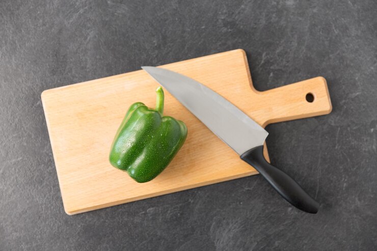Foto pimienta verde y cuchillo de cocina en la tabla de cortar