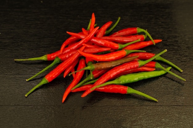 Pimientas de chile candentes en fondo de madera negro