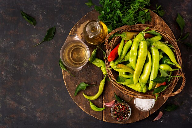 Pimientas de chile verde en una cesta en un fondo oscuro. Preparación para el decapado. Endecha plana.