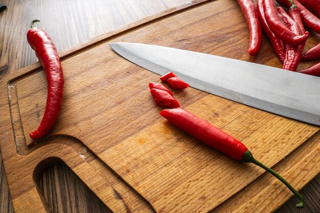 Pimientas rojas pepperoni picadas en la tabla de cortar con un cuchillo