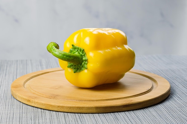 Pimiento amarillo grande sobre una tabla de cortar de madera. Consumo habitual de verduras.