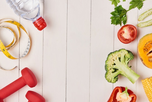 Pimiento con cinta métrica, pesas y botella de agua, aislado en blanco