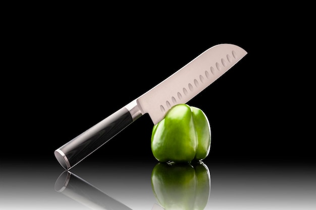 Pimiento de corte de cuchillo de chef profesional sobre fondo negro con reflexión. Las mejores herramientas para cocina y restaurante. El mejor cuchillo para cocinar.