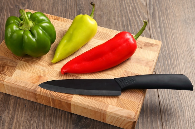 Foto pimiento dulce con un cuchillo de cerámica sobre una tabla de madera. alimento vitamínico útil
