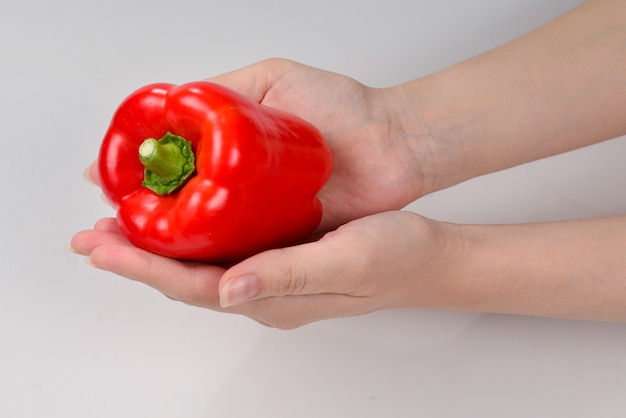 Pimiento en mano de mujer aislado en blanco.