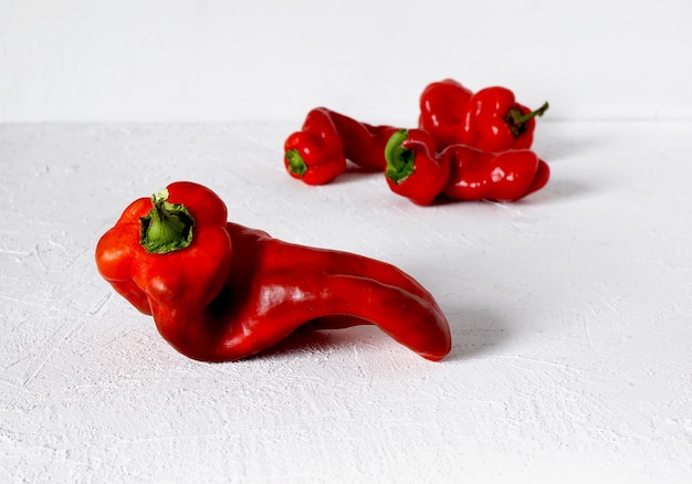 Foto pimiento rojo feo sobre un fondo blanco y más pimientos en el fondo