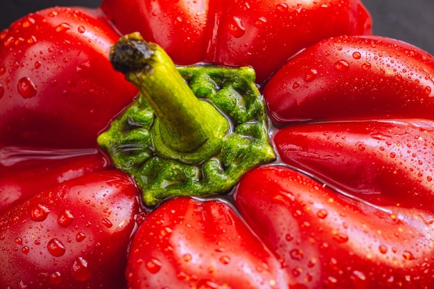 Foto pimiento rojo fresco sobre fondo negro vista superior fondo abstracto tropical cloe up pimienta verduras con gotas de agua