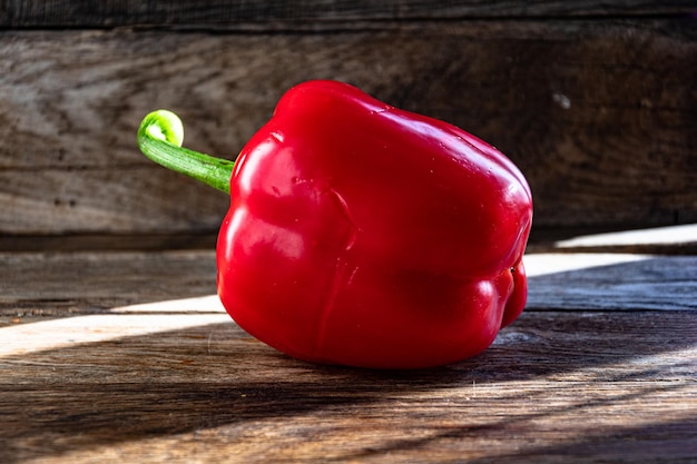 Pimiento rojo maduro en una mesa de cocina de madera.