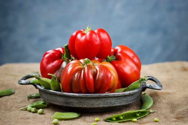 Pimiento rojo en una placa de metal con guisantes sobre una mesa