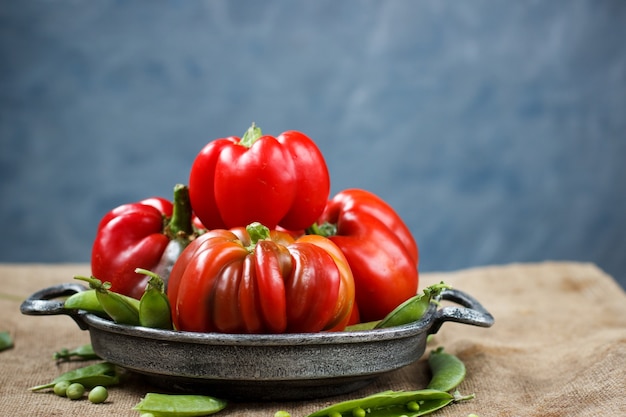 Pimiento rojo en una placa de metal con guisantes sobre una mesa