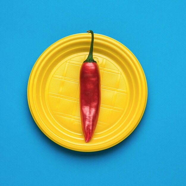 Pimiento rojo en un plato amarillo sobre un fondo azul.