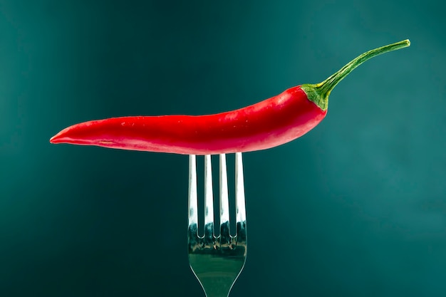 Pimiento rojo con primer plano de la horquilla en la oscuridad. Vitaminas y alimentos vegetales saludables