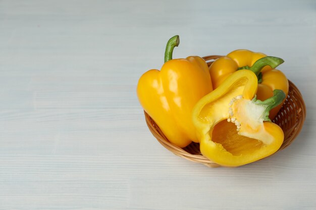 Pimiento en un tazón de mimbre sobre fondo blanco de madera