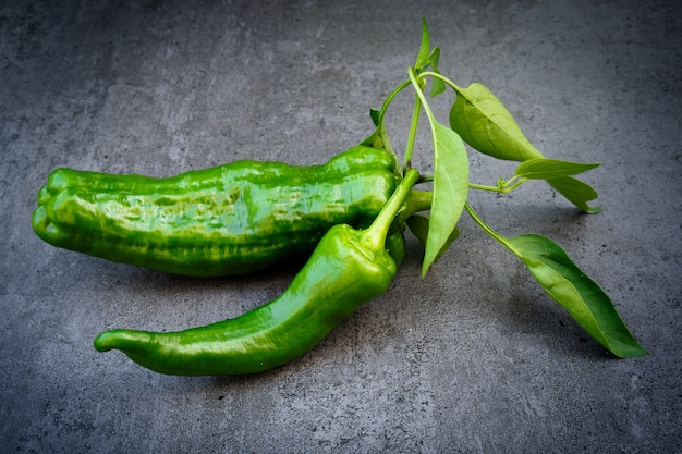 Pimiento verde con hojas sobre fondo oscuro