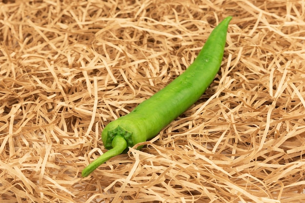 Pimiento verde con paja vegetal de pimiento picante en una hierba de paja de heno