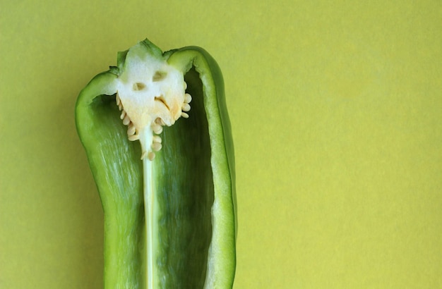 Pimiento verde en la sección con cara creativa sobre un fondo amarillo