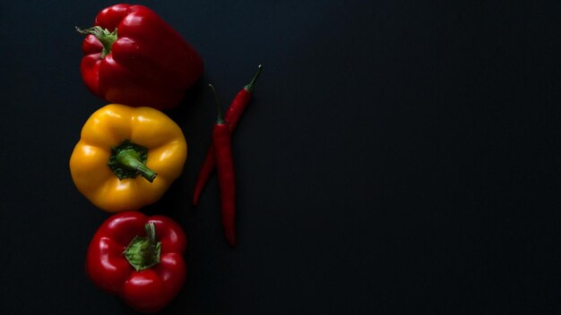 Foto pimientos búlgaros y chiles aislados en un fondo oscuro vegetales frescos