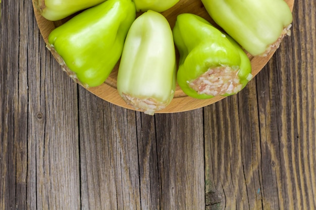 Pimientos crudos rellenos de carne sobre una tabla para cortar madera