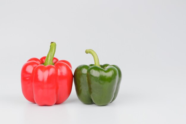 Pimientos dulces rojos y verdes aislados en blanco