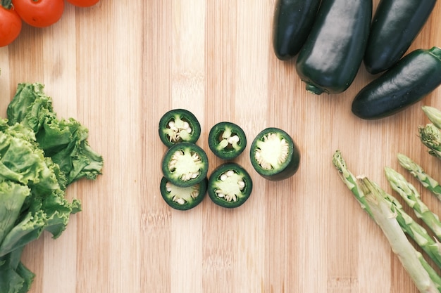 Pimientos jalapeños espárragos tomate cherry lechuga sobre una tabla de cortar