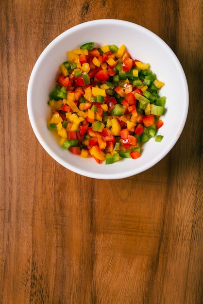 Pimientos multicolores cortados en cubos en un recipiente de metal sobre una mesa de madera Ensalada colorida