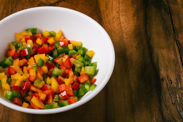 Pimientos multicolores cortados en cubos en un recipiente de metal sobre una mesa de madera Ensalada colorida