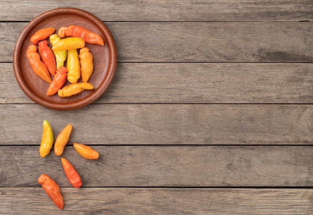 Pimientos de naranja cheiro (olor, aroma) en un plato sobre la mesa de madera con espacio de copia.