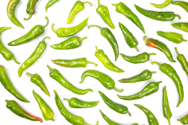 Foto los pimientos picantes verdes se distribuyen uniformemente sobre un fondo blanco. vegetales vitaminados para la salud