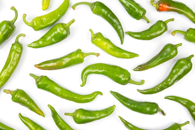 Foto pimientos picantes verdes repartidos uniformemente sobre un fondo blanco. vegetales vitamínicos para la salud