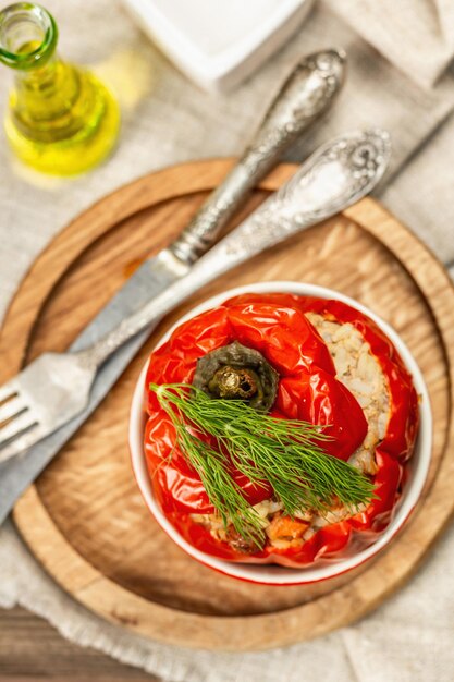 Pimientos rellenos de carne y arroz caseros. Aceite de oliva, salsa, cubiertos. Comida sana tradicional, fondo de madera vintage, vista superior