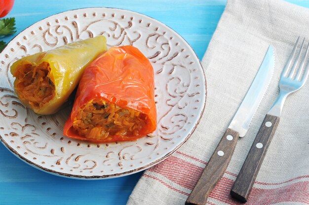 Pimientos rellenos de zanahoria y hierbas sobre superficie de madera azul