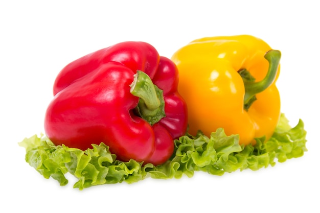 Los pimientos rojos y amarillos están en la hoja de lechuga sobre un fondo blanco.