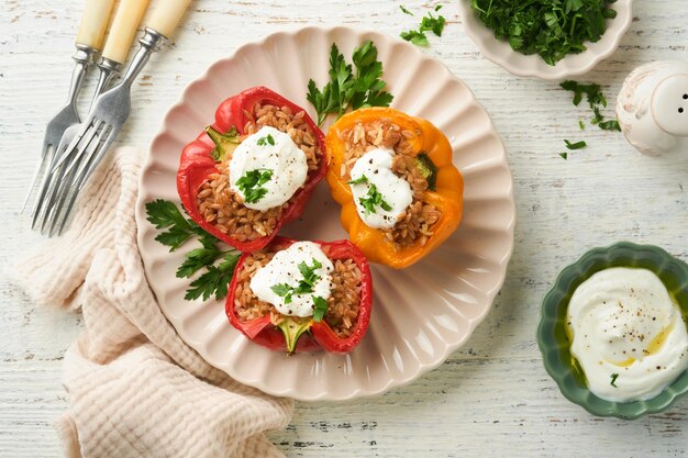 Pimientos rojos y amarillos rellenos asados con arroz integral de cuscús y espelta con salsa griega y aceite de oliva sobre fondo rústico de madera Cena saludable comer Concepto de cena acogedora de otoño Vista superior