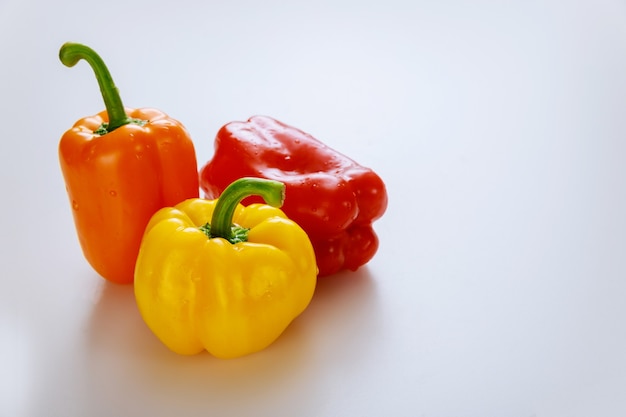 Pimientos rojos, naranjas y amarillos aislados sobre fondo blanco. Copie el espacio.