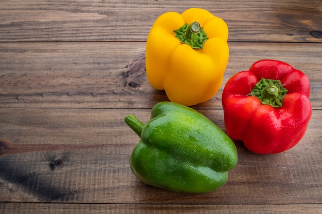 pimientos rojos, verdes y amarillos sobre fondo de madera