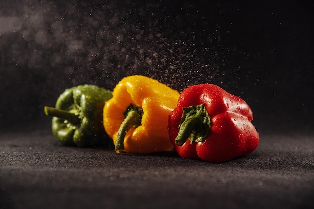 Pimientos sobre fondo negro paprika con gotas de verduras para el restaurante