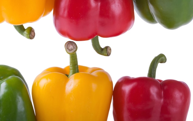 Pimientos verdes amarillos y rojos sobre fondo blanco.