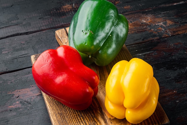 Pimientos verdes, amarillos y rojos, sobre la vieja mesa de madera oscura.