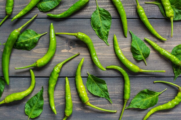 Pimientos verdes y hojas en la mesa de madera vieja