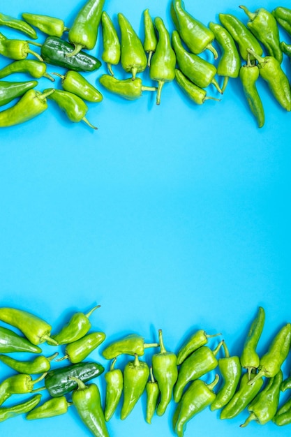 Foto pimientos verdes largos de diferentes tamaños y tonos de verde sobre un fondo azul