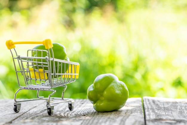 Pimientos verdes en un pequeño carrito de compras.