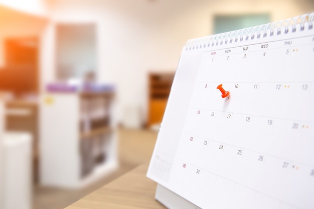 Un pin de color rojo en el calendario en blanco