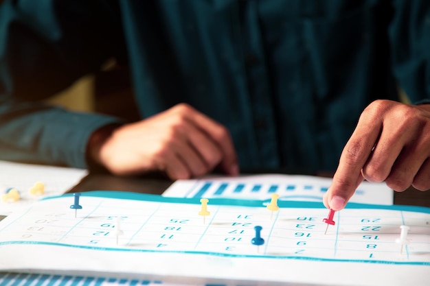 Foto pin de mano en el calendario de escritorio de negocios con el concepto de equipo de oficina de planificador de eventos o recordatorio de organización personal y programación o planificación