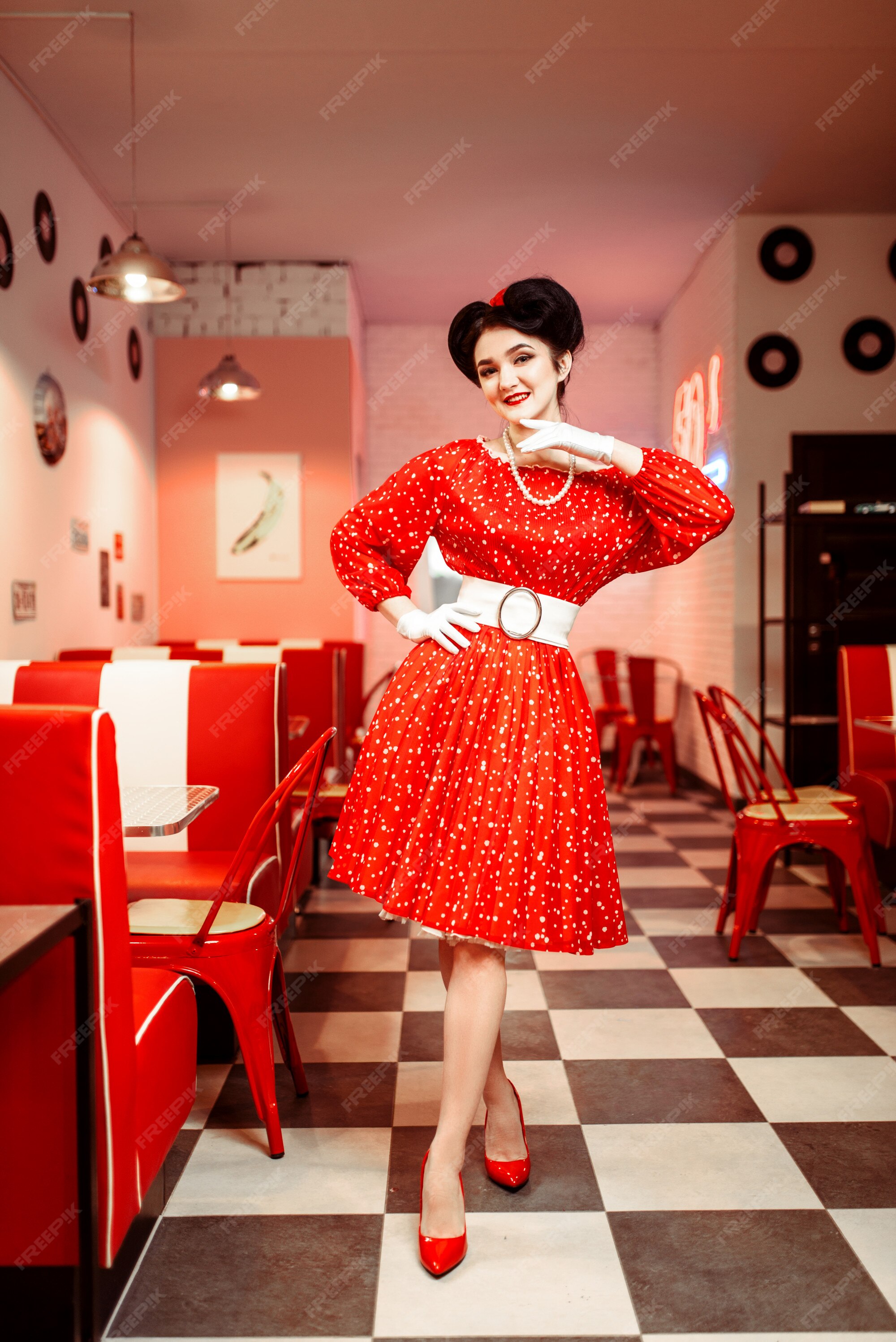 Pin up mujer vestido rojo con estilo vintage. interior de café retro con piso de tablero de ajedrez | Foto Premium