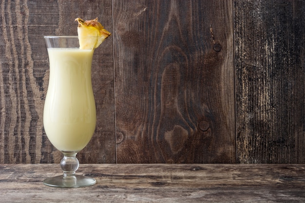 Piña colada cocktail em vidro na mesa de madeira