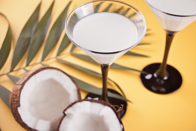 Pina colada cocktail na mesa amarela com folha de palmeira e coco no fundo